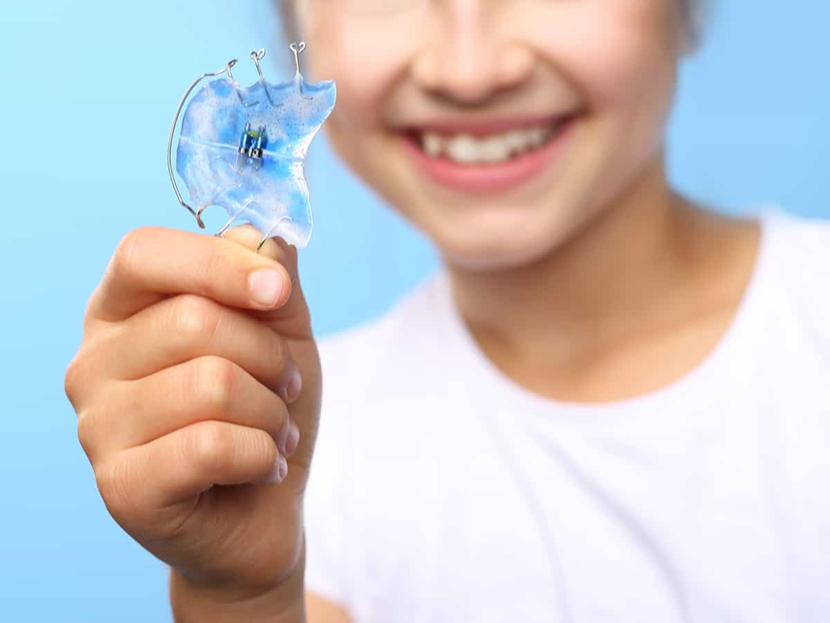 Young dental patient holding retainers