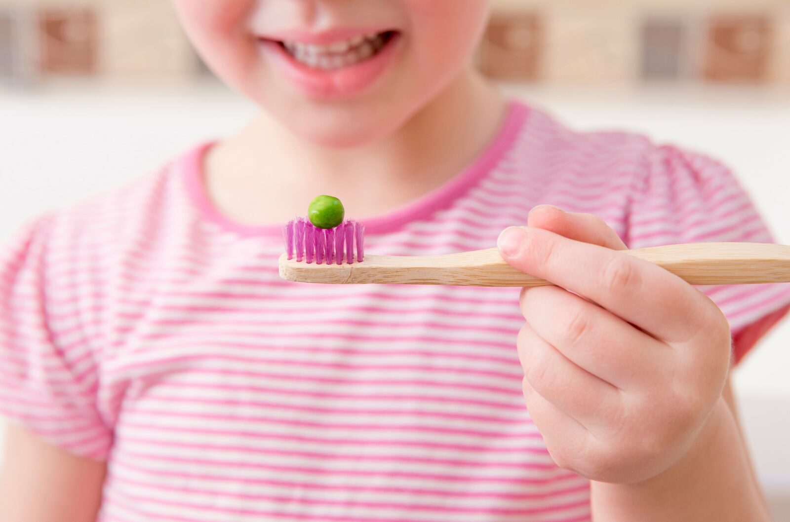 young girl with a pea on her toothbrush to indicate proper toothpaste use